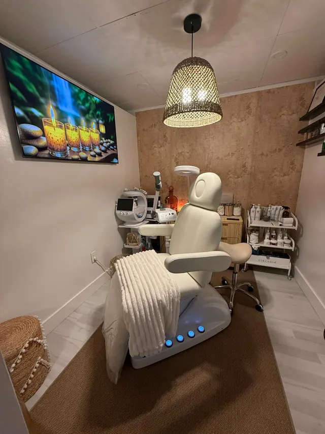 Cabina de faciales de ELLE Beauty Spa con camilla blanca, lámpara de mimbre y pantalla con velas